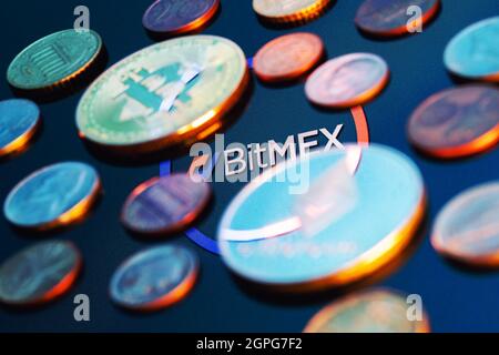 BitMEX ist eine Kryptowährungsbörse und eine derivative Handelsplattform. BitMEX-Logo, umgeben von verschwommenen Münzen. Stockfoto
