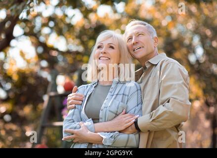 Glückliche ältere Ehepartner genießen warme Herbsttage und friedliche Natur, Mann umarmt Frau, freien Raum Stockfoto