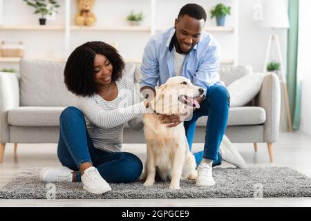 Glückliches schwarzes Paar, das Zeit zu Hause mit labrador verbringt Stockfoto