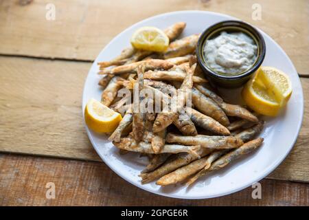 Frittierte Sprossen, Sprattus Sprattus, serviert mit Zitronenkeilchen und Tartaresauce, gefangen in Lyme Bay Dorset. Sprotten sind ein kleiner, schhohlender Fisch, der ar Stockfoto