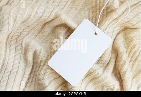 Nachbildung eines Preisschildes oder Etiketts aus weißem Papier auf warmem Sweatshirt im Hintergrund Stockfoto