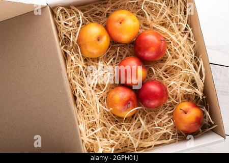 Mehrere saftige, süße gelb-rote Pflaumen in einer Schachtel mit Schälen, Nahaufnahme, Draufsicht. Stockfoto