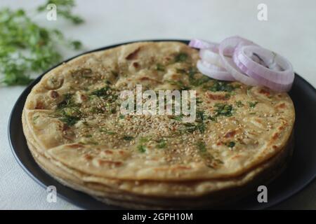 Perfekt runder Paratha. Indisches Fladenbrot aus Weizenmehl, gekrönt mit Sesamsamen und Korianderblättern. Aufgenommen auf weißem Hintergrund Stockfoto