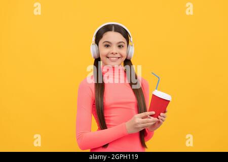 Lassen Sie uns versuchen. Fröhliches Kind mit Take Away Kaffeetasse mit Kopfhörern. Guten Morgen Stockfoto