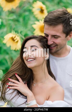 Schöne wunderschöne Frau und stilvolle gut aussehende männliche, rustikale Paar in einem Sonnenblumenfeld küssen Stockfoto