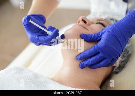 Nadelmesotherapie im Schönheitssalon oder in der Klinik. Kosmetik wurde ins Gesicht der Frau injiziert, Nahaufnahme Porträt Stockfoto