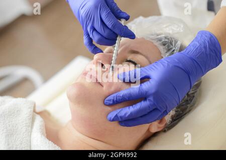 Nadelmesotherapie im Schönheitssalon oder in der Klinik. Kosmetik wurde ins Gesicht der Frau injiziert, Nahaufnahme Porträt Stockfoto