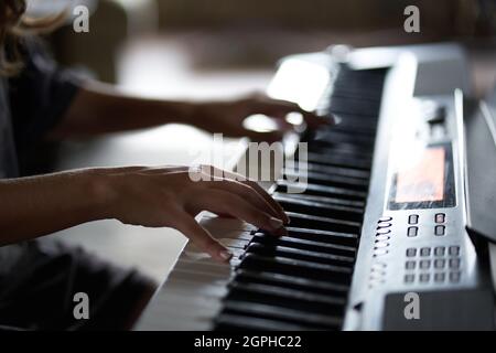 Die Hände des Musikers auf dem Synthesizer. Ein zugeschnittenes Bild einer Person, die einen Synthesizer spielt. Seitenansicht. Hochwertige Fotos Stockfoto