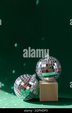 Stillleben mit Holzwürfeln und Diskokugel, die Sonneneruptionen vor smaragdgrünem Hintergrund reflektiert Stockfoto