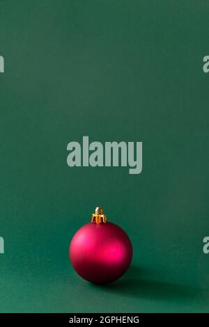 Rote Weihnachtskugel vor smaragdgrünem Hintergrund Stockfoto