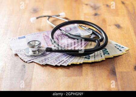 Euro-Banknoten und Stethoskop auf Holztisch. Stockfoto