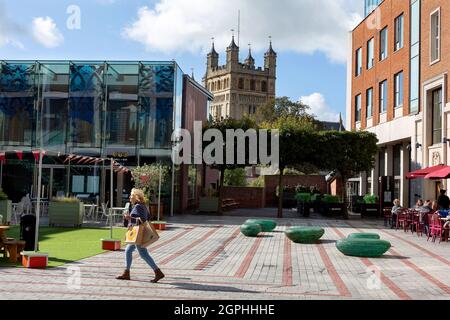 Ein Einzelkäufer im Princesshay Einkaufszentrum mit dem Turm der Kathedrale von Exeter im Hintergrund. Stockfoto