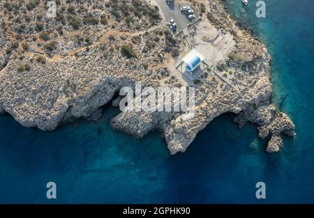 Drohnenantenne Kap Greko Halbinsel. Agioi Anargyroi Kirche auf den Felsen. Kreuzfahrt touristische Boote segeln Zypern. Stockfoto