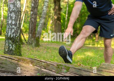 Ein junger, dauerhafter Athlet streckt sich im Wald draußen, um den Wald herum, Eichen. Athlet Erholung Bewegung, Bäume Mann. Adul Stockfoto