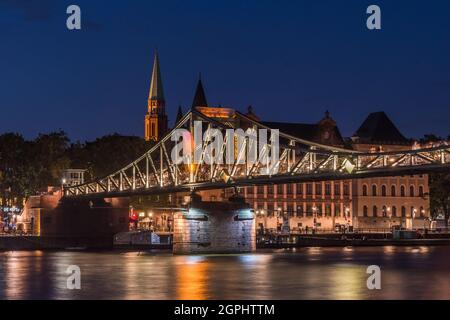 Die beleuchtete Fußgängerbrücke namens Eiserner Steg, die nachts den Main in Frankfurt überquert Stockfoto