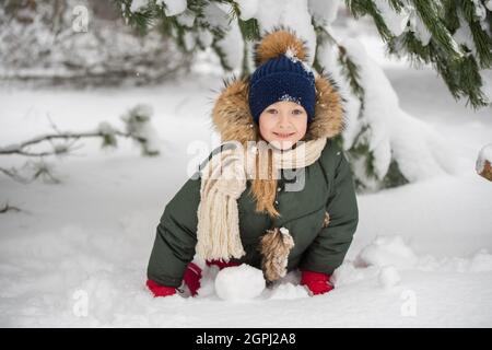 Glückliches Mädchen, das auf einem verschneiten Winterspaziergang mit Schnee schneit Stockfoto