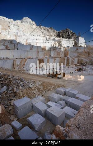 Carrara-Marmorbrüche, viereckige weiße Marmorblöcke auf dem Steinbruch von Gioia, Bulldozer ...