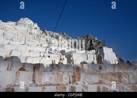 Carrara-Marmorbrüche, viereckige weiße Marmorblöcke auf dem Steinbruch von Gioia, Bulldozer ...