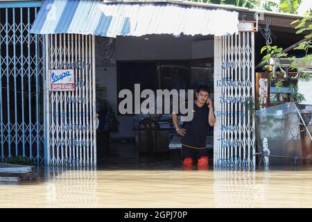 Lopburi, Thailand. September 2021. Ein Mann benutzt sein Mobiltelefon in einem überfluteten Haus, als der Pasak Jolasid-Staudamm überläuft. Nach Angaben der Royal Irrigation Department (RID) verursachten der tropische Sturm Dianmu und eine aktive Niederdruckzelle weitverbreitete Überschwemmungen. Es wurde erwartet, dass zwischen dem 27. September und dem 3. Oktober etwa 515 Millionen Kubikmeter Abfluss in den Staudamm von Pasak Jolasid fließen würden. Wenn die Entladungsrate bei 8.64 Millionen Kubikmeter pro Tag bleiben würde, würde der Staudamm am 30. September seine Kapazität erreichen. (Foto von Chaiwat Subprasom/SOPA Images/Sipa USA) Quelle: SIPA USA/Alamy Live News Stockfoto