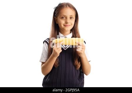 Schulmädchen in einer Uniform, die Mais auf dem Kob isst, isoliert auf weißem Hintergrund Stockfoto