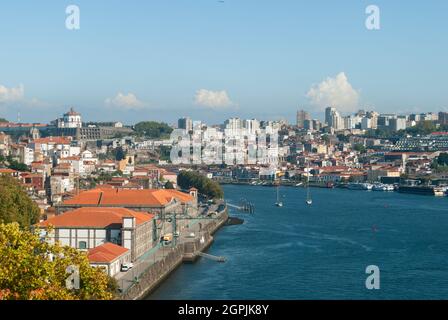 Landschaftsansicht von Porto und Gaia ribeira an einem sonnigen Tag mit Yachten und Booten, die an rot gefliesten Dächern vorbeifahren - Porto, Portugal Stockfoto