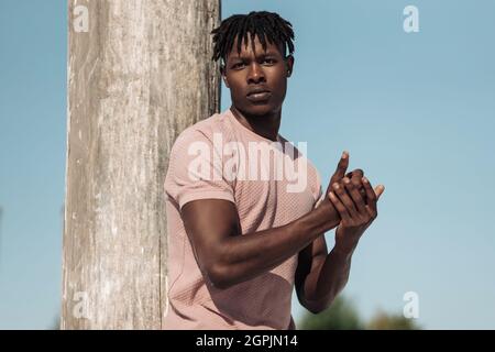 Porträt eines modischen afroamerikanischen Mannes mit Afro-Haaren, Mann posiert in exotischer Wüste, Sanddünen herum, Modelkonzept Stockfoto