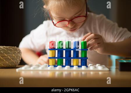 Ein Mädchen mit Down-Syndrom entwickelt feinmotorische Fähigkeiten und bereitet sich mit Hilfe von Numikon auf das Studium der Mathematik in der ersten Klasse vor Stockfoto