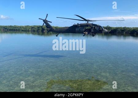 KEY WEST, Florida – Ein Hubschrauber der UH-60 Blackhawk transportiert Green Berets mit dem 1. Bataillon, der 1. Special Forces Group (Airborne) und den Küstenwachleuten des US-Küstenwachensektors Key West während des Wasserinfiltrationskurses in Key West, Florida, im September 2021. Dieser Kurs schult die Studenten in Techniken zur Oberflächeninfiltration auf Wasserbasis unter Verwendung eines Kampfflugzeugs, das Kautschuk überführt. (USA Foto der Armee) Stockfoto