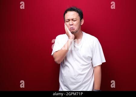 Zahnproblem des jungen asiatischen Mannes mit verletzten Emotionen tragen schwarzes Hemd. Stockfoto