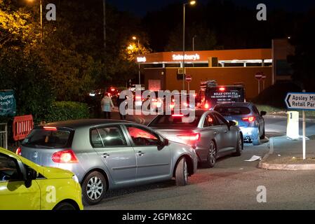 Apsley, Hertfordshire, Großbritannien. September 2021. Am frühen Abend im Dunkeln stehen die Autofahrer an der Tankstelle Apsley von Sainsbury an, um sich zu füllen. Autos, die sich mit ihren Lichtern an der Zufahrtsstraße zum Apsley Mills Retail Park anstellen, die zur Tankstelle führt. Frühere Autofahrer hatten sich schon einige Zeit in der Schlange gestellt, bevor ein Tanker, der bleifreies E10-Benzin lieferte, seine Ladung abgab. Viele Tankstellen in Hertfordshire und den umliegenden Grafschaften wurden geschlossen. Kredit: Stephen Bell/Alamy Stockfoto