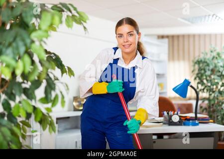 Eine junge Frau aus einer Reinigungsfirma führt eine Nassreinigung des Büros durch Stockfoto