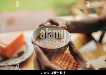 Hände halten Hot Coffee Americano im Coffee Shop. Kaffee- und Dessertkonzept. Stockfoto