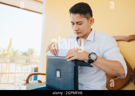 Ziehen Sie das Papierdatenblatt von Hand aus der Laptoptasche Stockfoto