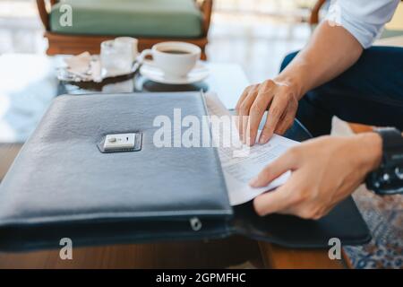 Ziehen Sie das Papierdatenblatt von Hand aus der Laptoptasche Stockfoto