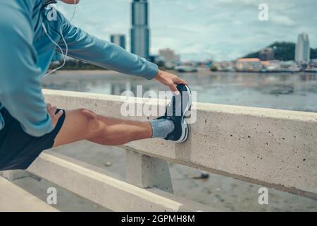 Junger Mann, der sich vor dem Laufen im Park ausdehnt. Junger Mann trainieren vor dem Fitnesstraining im Park. Gesund und Bewegung junger Mann Aufwärmen auf t Stockfoto