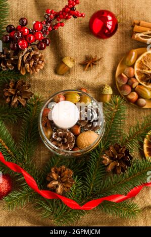 Weihnachtsdekoration mit eigenen Händen, um ein Haus oder einen Tisch für einen Urlaub zu dekorieren. In einer Glasvase Kerze, Nüsse, Zapfen, Eicheln. Draufsicht Stockfoto