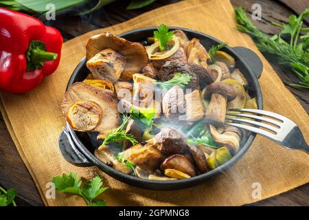 Garen Sie einfach dampfende Steinpilze in der Pfanne auf dem Holztisch. Draufsicht. Stockfoto