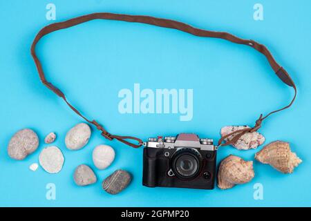 Kamera und Muscheln auf blauem Hintergrund.Hintergrund für den Reisenden. Stockfoto