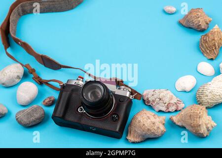 Kamera und Muscheln auf blauem Hintergrund.Hintergrund für den Reisenden. Stockfoto