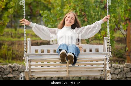 Glückliches Kind schwingt auf Schaukel im Freien, Sommer Stockfoto