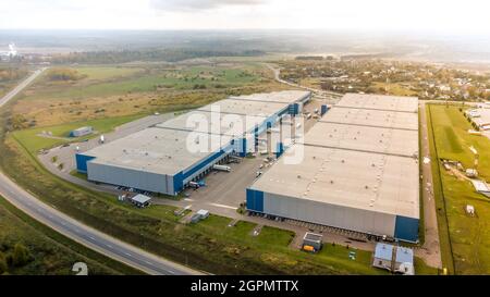 Luftaufnahme des Industrielagers. Lade-Nabe und viele LKW mit Laderampen. Luftaufnahme des Warenlagers. Modernes Distributionszentrum von Stockfoto