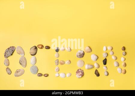 Die Inschrift des Wortes Ozean aus Muscheln auf einem gelben Hintergrund.Reisekonzept. Stockfoto