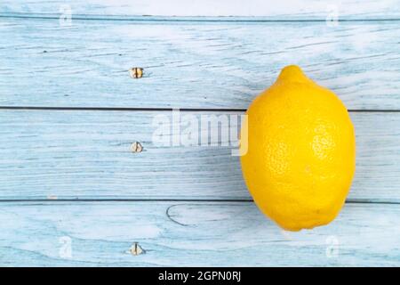 Eine ganze gelbe Zitrone liegt auf einem blauen Holzhintergrund. Stockfoto