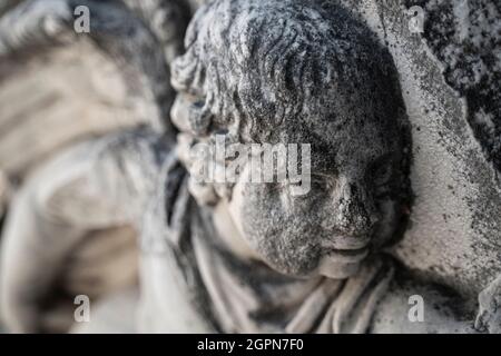 Nahaufnahme der perspektivischen Ansicht des alten Steinbasorelief des Kinderkopfes auf dem Postament eines alten Gebäudes Stockfoto