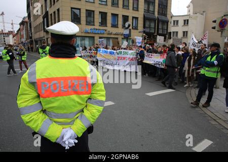 Ein Polizist steht Wache, während junge Demonstranten an einer Demonstration in Nürnberg im Rahmen der Studentenfreitags-Kampagne teilnehmen, die auf mich abzielt Stockfoto