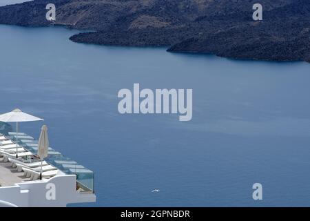 Spektakuläre Aussicht auf die Caldera und den Vulkan von Santorini von einem Luxushotel mit Sonnenliegen Stockfoto