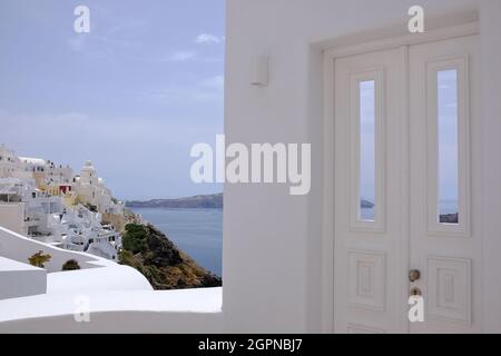 Eine wunderschöne weiß getünchte Tür und das malerische Dorf Fira von Santorini Griechenland im Hintergrund Stockfoto