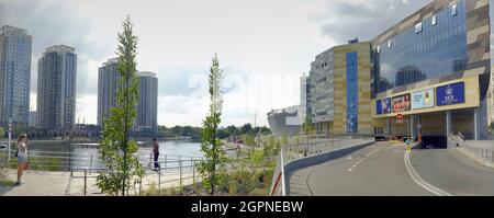 Kiew, Ukraine - 24. Juli 2021: Wolkenkratzer spiegeln sich im Wasser des Teiches. Stadt an einem sonnigen Tag. Stadtpark Stockfoto