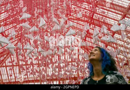 Eine Dame betrachtet das Herzstück mit dem Namen „One Thousand Springs“, das der japanische Künstler Chiharu Shiota während einer Fotoschau für das Japan Festival, das eine Feier der atemberaubenden Pflanzen, Kunst und Kultur des Landes darstellt, im Royal Botanic Gardens, Kew, London, erstellt hat. Bilddatum: Donnerstag, 30. September 2021. Stockfoto