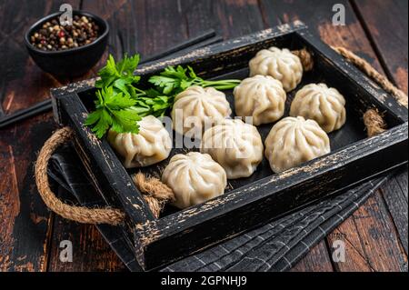 Momo Knödel in einem Holztablett mit Kräutern. Dunkler Holzhintergrund. Draufsicht Stockfoto